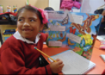 A child smiling in front of her desk