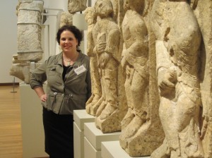 Marianne Eileen Wardle standing with limestone reliefs of four apostles, c. 1125-1150, at the Nasher Museum of Art at Duke University. Wardle is Andrew W. Mellon Curator of Academic Programs at the Nasher and a Duke PhD alumna.  