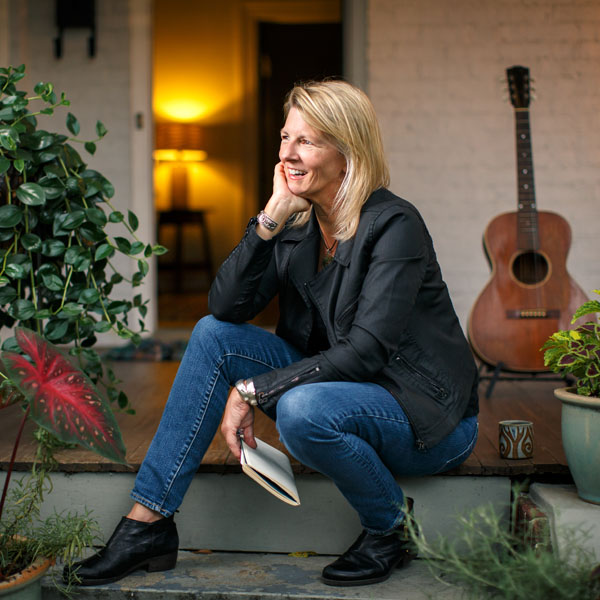 Woman sitting on front porch with guitar in the background.