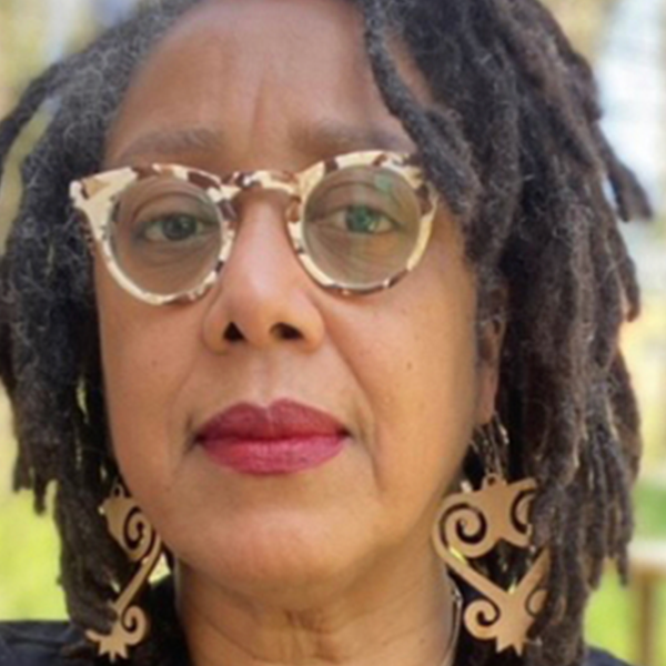 Person with tortoiseshell glasses and Sankofa earrings