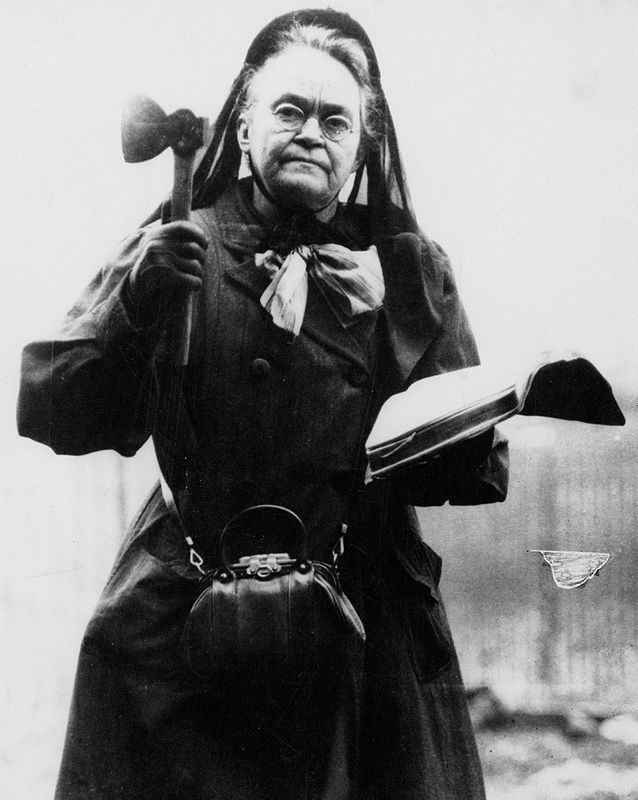 Portrait of Carrie Nation holding her hatchet in her right hand and the Bible in her left.