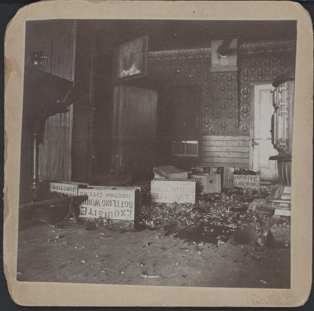 A saloon completely destroyed with broken glass, ripped floorboards, and crates of alcohol on the ground