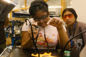 A student carefully holding a filament and experimenting with electricity