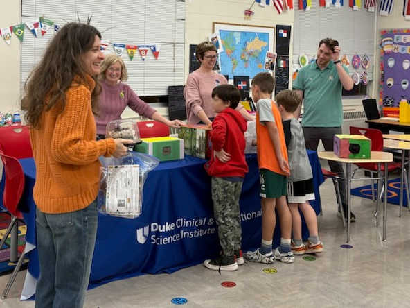 Students at table guessing the identity of health and safety items in mystery boxes