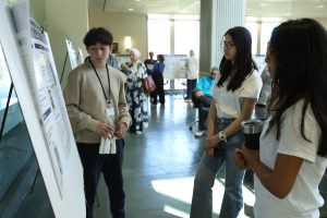 Ignite participant presenting a poster and model to students