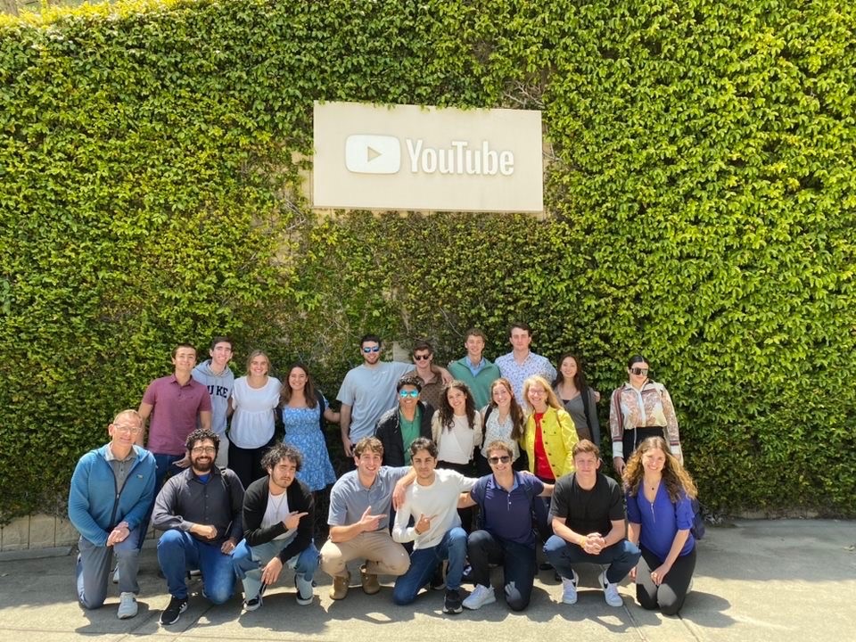 A group photo with YouTube sign and ivy wall in background