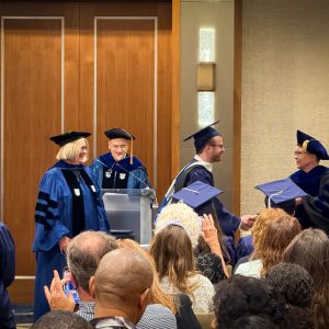 students and faculty in graduation regalia
