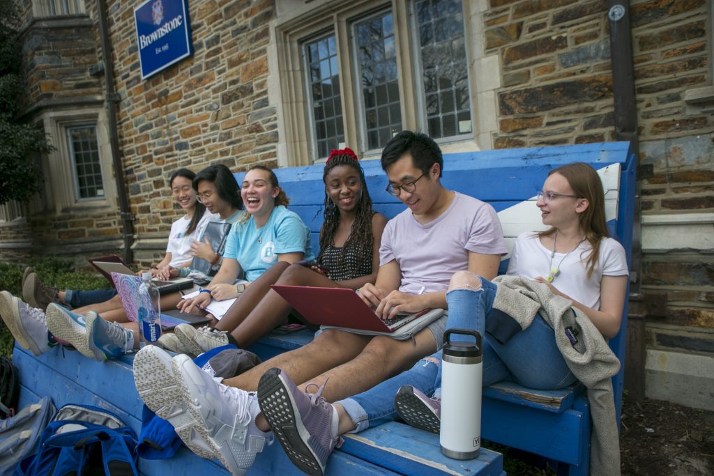 Brownstone dorm roommates, enjoy an unusually warm February afternoon to study and socialize outside.
