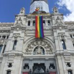 A big white palace in Madrid with LGBTQ+ flag