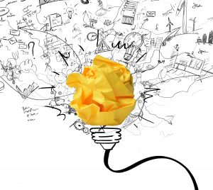 Crumpled yellow paper drawn as a lightbulb with drawings emanating from it