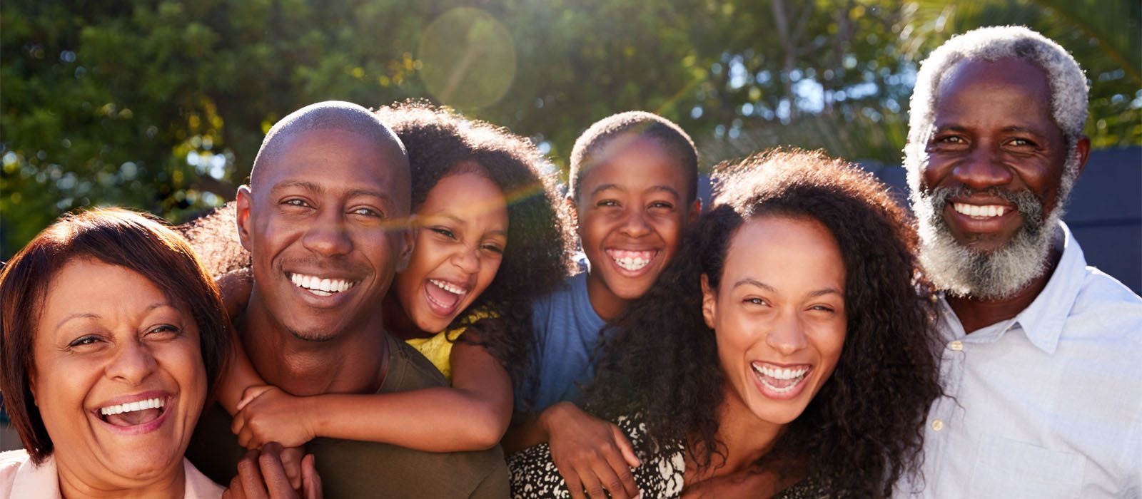 Outdoor Portrait Of Multi-Generation Family In Garden At Home Against Flaring Sun