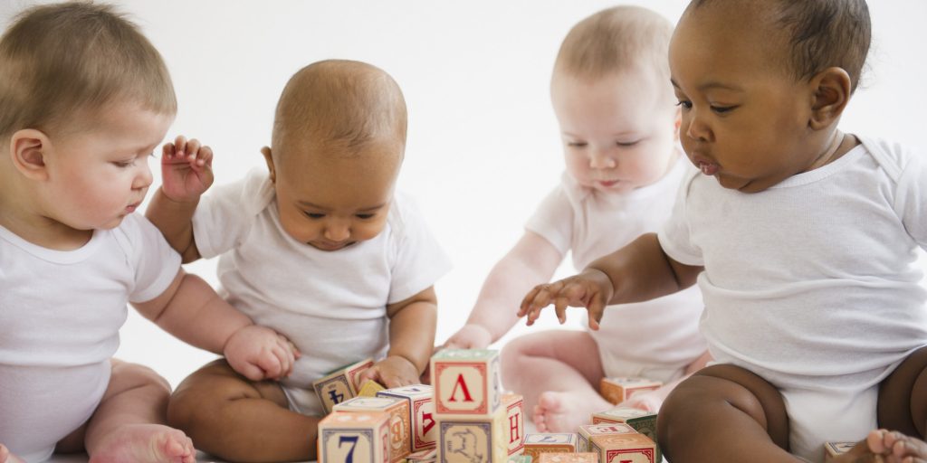 four babies playing with blocks