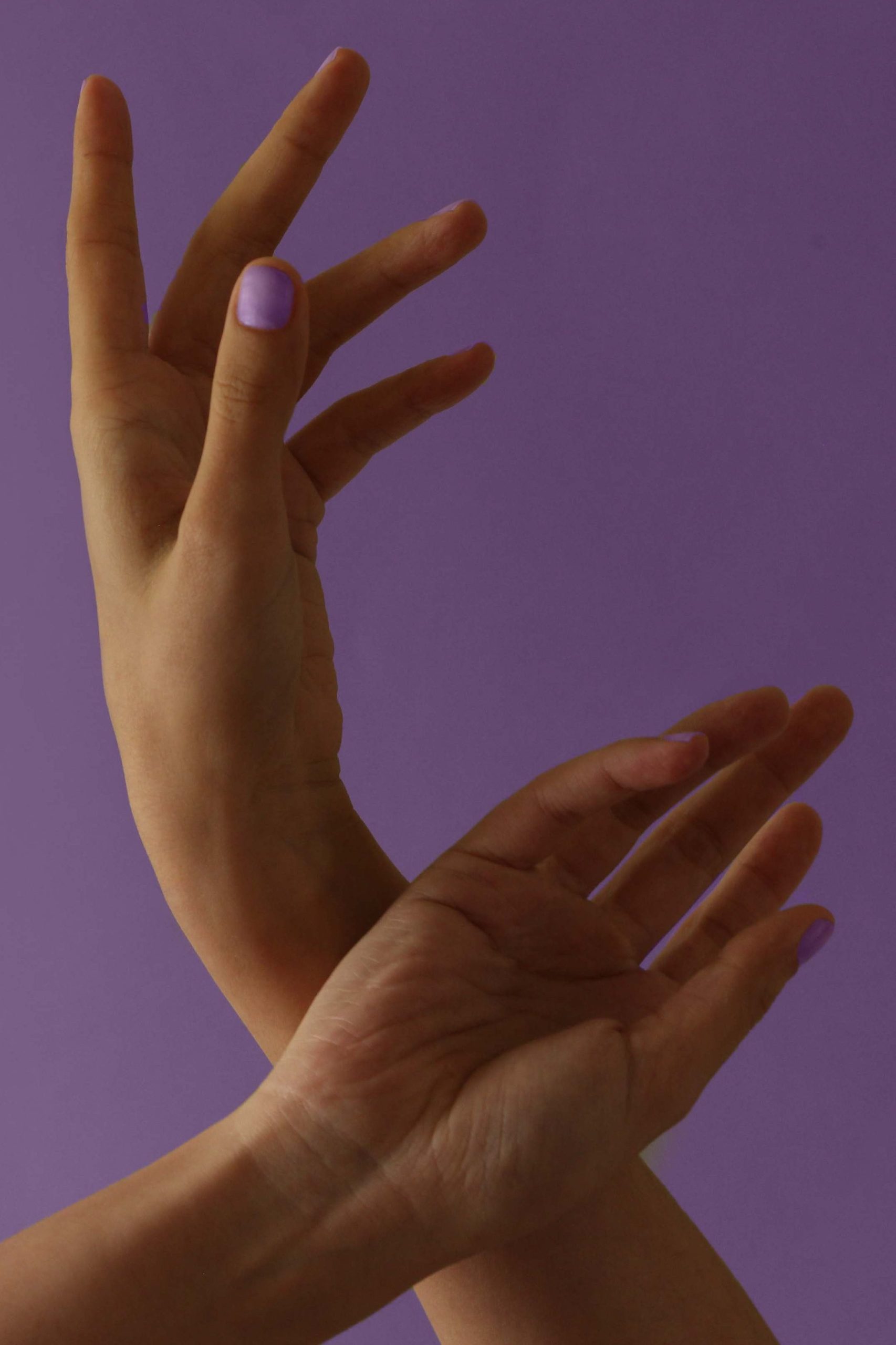 hands crossed in front of a purple background